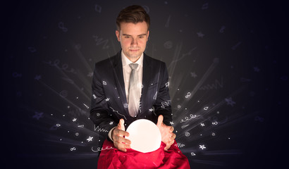 Gorgeous businessman looking to inspiration in a magic ball in his lap and doodle concept
