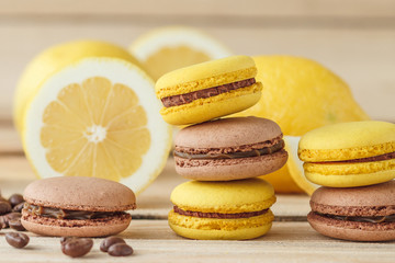 Yellow and brown french macarons with lemons and coffee beans on the wooden board