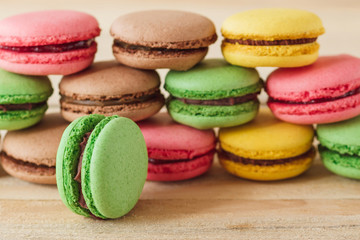 Green, pink, yellow and brown french macarons on the wooden boards