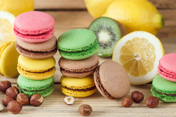 Green, pink, yellow and brown french macarons with lemon, kiwi and hazelnuts