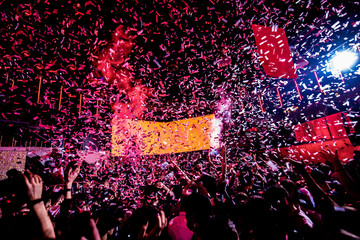 Confetti fired on air during a concert. People are happy and with hands in the air. Image ideal for backgrounds. Red is the tone of the picture