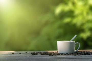 Coffee cup and coffee beans on vintage wooden table top in morning sunlight