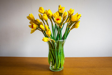 Daffodils in a glass vase on wooden table