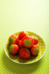 green yellow plate with red strawberries with copy space
