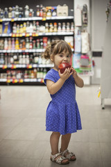 Little girl eating apple in the supermarket