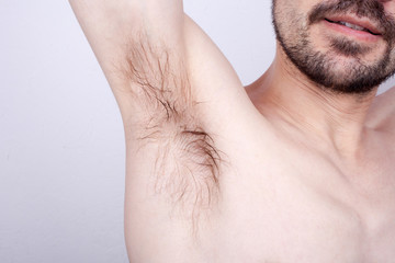The man raised his hand up, and shows unshaven armpit. Unpleasant smell.