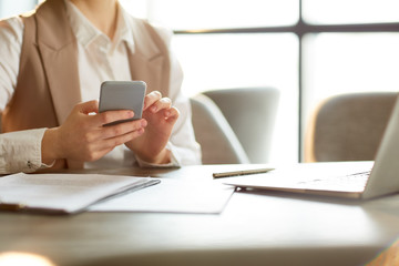 Fototapeta premium Hands of businesswoman with smartphone messaging or reading notification during work