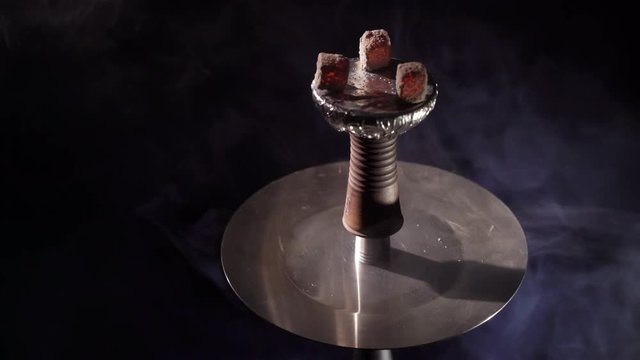Hookah bowl with coals and smoke on black background