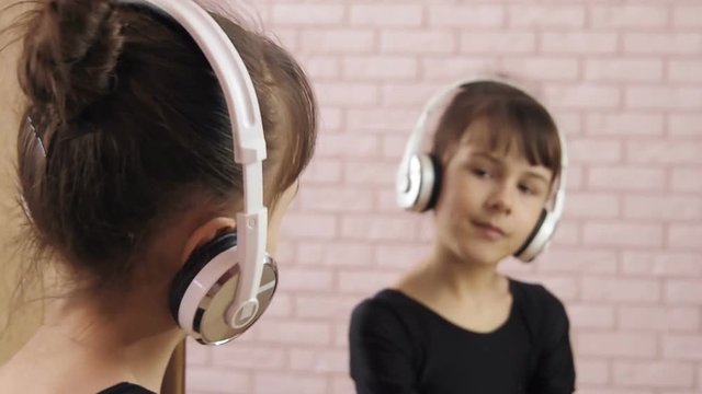 Girl in headphones. Little girl at the mirror in the headphones.