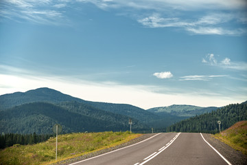 highway through hills and clouds on sky