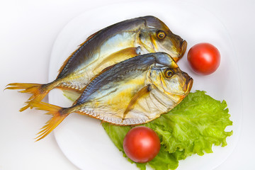 Smoked fish on white plate with vegetables on isolated backgroun