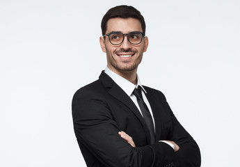 Horizontal shot of young successful smilling business man with crossed arms and side look. CEO,...