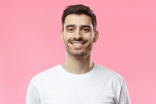 Close up portrait of smiling handsome man in white t-shirt isolated on pink background
