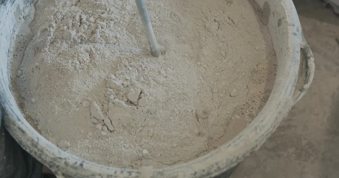 Slow motion handheld shot of mixing concrete plaster with electric mixer