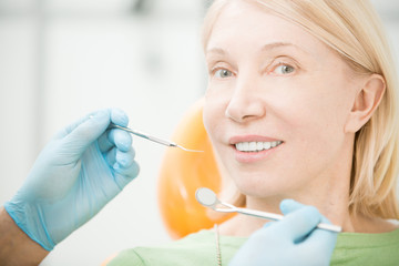 Mature blond woman looking at camera before dental check-up during visit to dentist