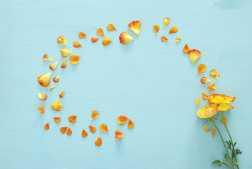 Image of delicate pastel orange and yellow beautiful flowers with petals arrangement over white wooden background. Flat lay, top view.