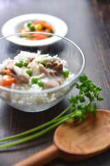 Chicken fricassee with green pea served with boiled rice on a wooden background.