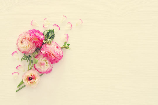 Image of delicate pastel pink beautiful flowers arrangement over white wooden background. Flat lay, top view. Vintage filtered.