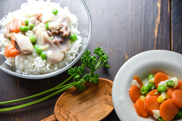 Chicken fricassee with green pea served with boiled rice on a wooden background.