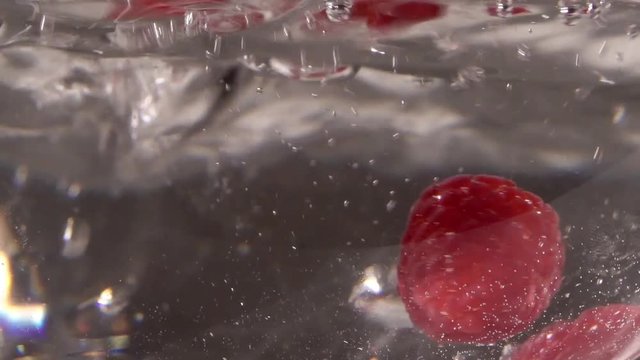 Raspberry drops in water with sparkles slowmotion
