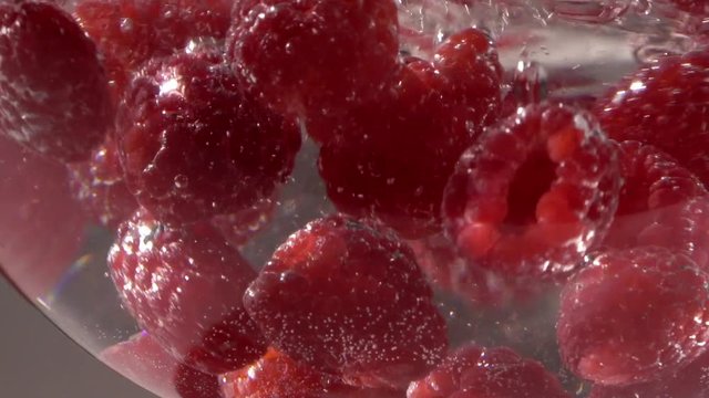 Raspberry drops in water with sparkles slowmotion