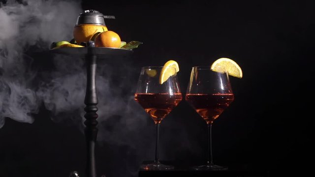 Pair of glasses with alcoholic drink beverage wine cocktail and hookah with fruits black background isolated