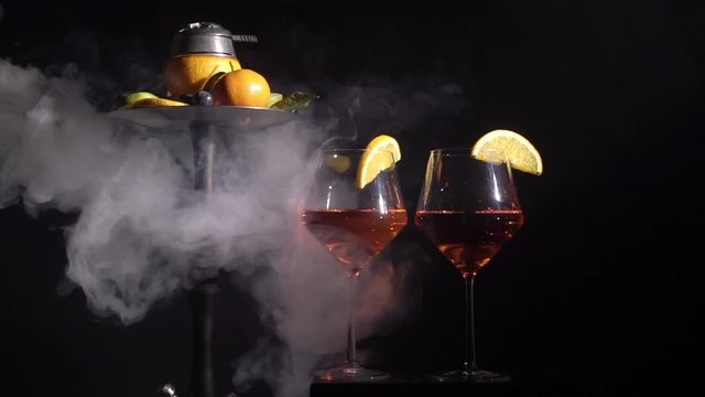 Pair of glasses with alcoholic drink beverage wine cocktail and hookah with fruits black background isolated