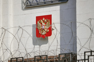 State coat of arms of Russia behind of barbed wire
