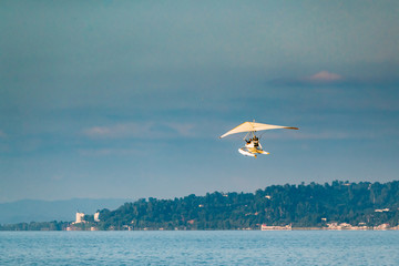 Motorized Hang Glider Flying In Sunny Sky