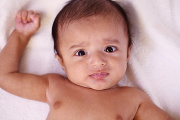 Playful newborn baby lying down in bed