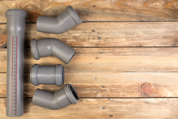 Assorted PVC sewage pipe fittings shot on the wooden background. Top view. Copy space for text.