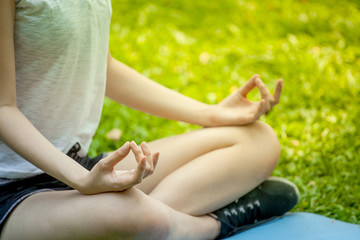 Close up hands woman meditation in the lotus position, hand of young fitness girl doing yoga in park morning light
