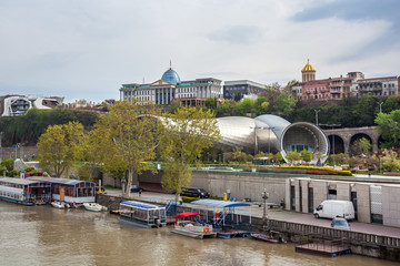 View over the modern glass Peace bridge to the President Palace and Trinity Cathedral