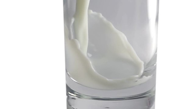 Pouring milk in long stream into a glass on white background