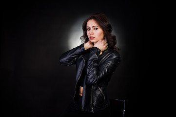 Obraz na płótnie Canvas Studio portrait of sexy brunette girl in black leather jacket against black background.
