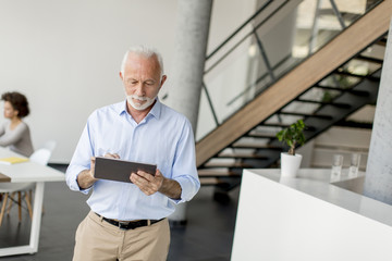 Senior businessman standing with digital tablet in his hand