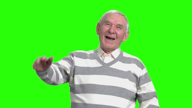Grandpa laughing at nonesense, slow-motion. Old man laughing because of hogwash against green background.
