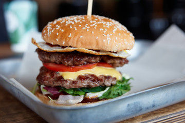Big burger on restaurant table, close-up, small focus depth