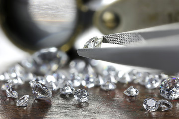 brilliant cut diamond held by tweezers - obrazy, fototapety, plakaty