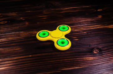 Yellow fidget spinner on wooden desk