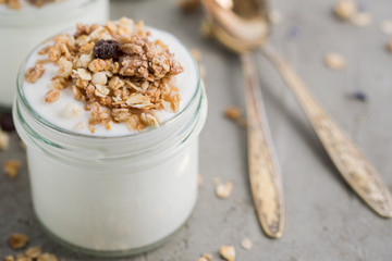 Yoghurt with granola made of oats, raisins, puffed rice, chocolate and dried bananas. Healthy breakfast for family.