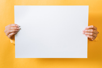 Hands with a business card punching a hole in a yellow background