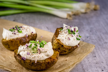 Baked potatoes with curd white cheese, red onion and chive - closeup