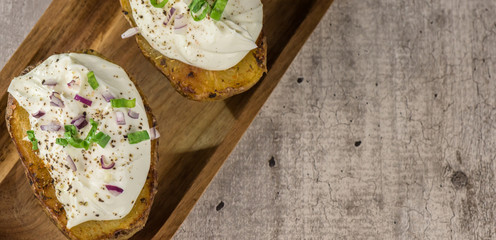Baked potatoes with curd white cheese, red onion and chive - closeup - banner - copy space