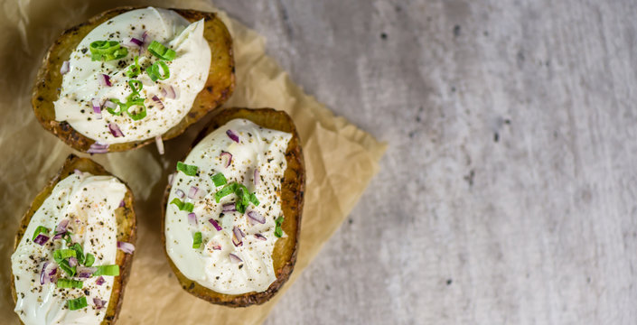 Baked potatoes with curd white cheese, red onion and chive - closeup - banner - copy space