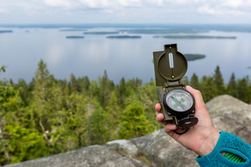 Naklejka premium Compass in hand and beautiful landscape on background, Koli National Park, Finland