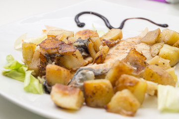 sea bass in the dish with potatoes and salad