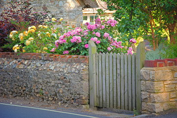 Garten mit Natursteinmauer und blühenden Rosen