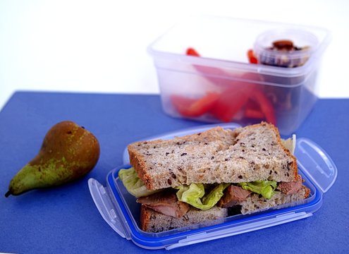 Lunch box for the student. Sandwich of corn bread with baked turkey and crispy lettuce leaves, pear, nut mix, sweet pepper