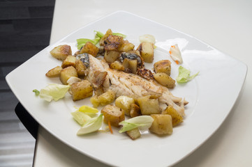 sea bass in the dish with potatoes and salad